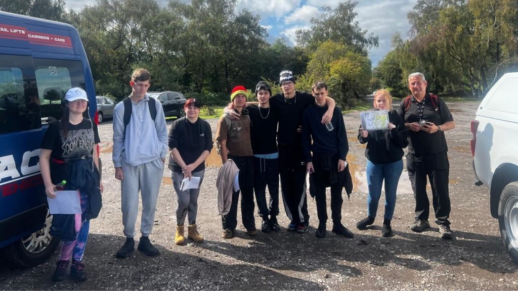 Group of young people standing by a minibus getting ready to start a hike
