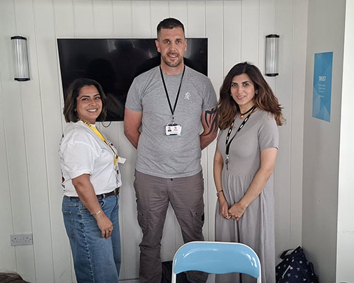 Two women and a man standing smiling to camera.